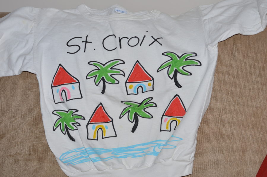 A white shirt with houses and palm trees painted on it.