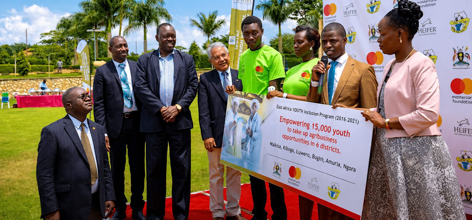 Group holding a large check for a donation with tropical plants in background.