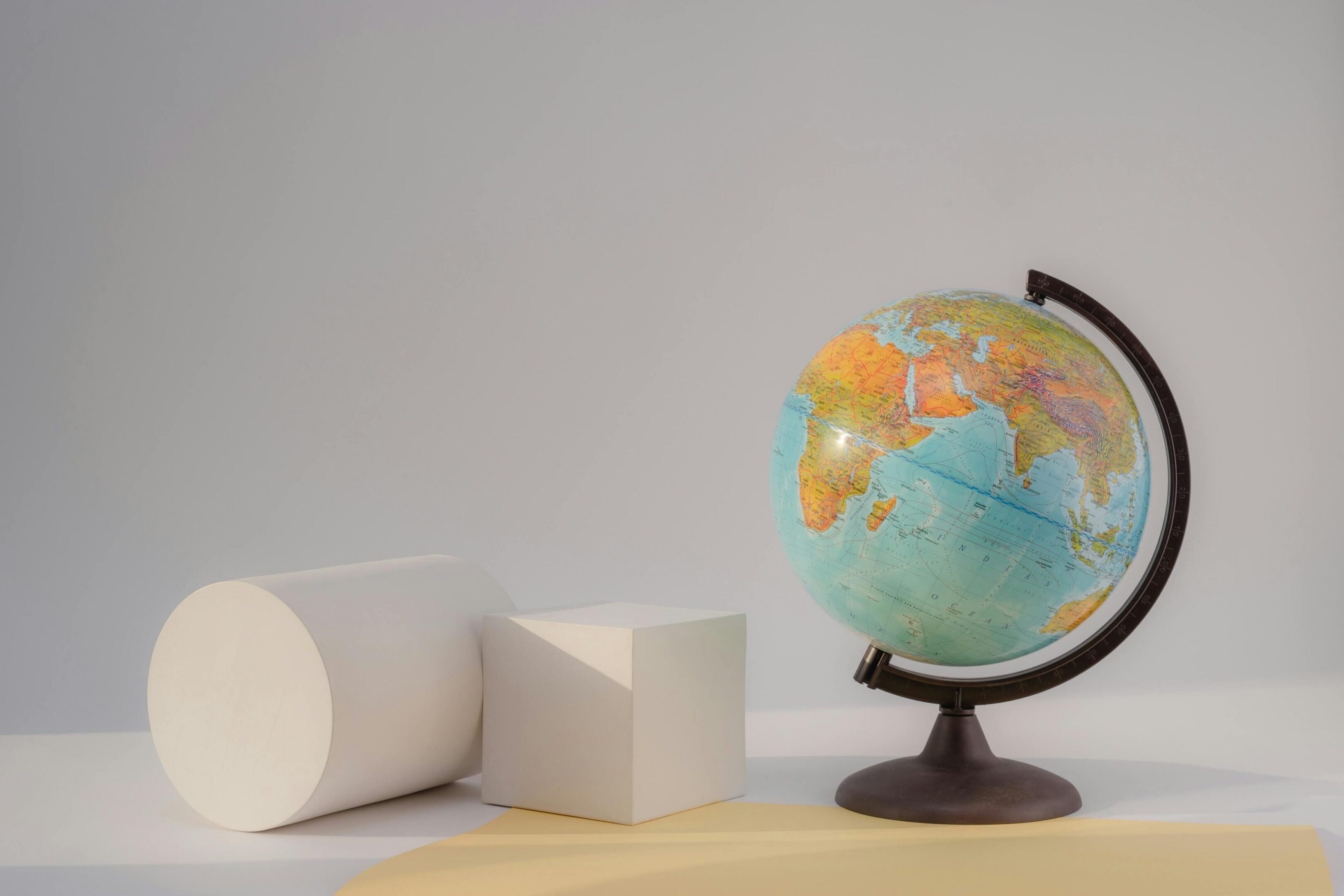 A globe beside white geometric shapes on a wooden surface.